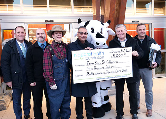 Group of employees standing together holding a giant cheque from Farm Boy to the Niagara Health Foundation. 