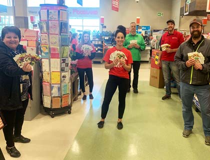 A group of Foodland employees and customers holding gift cards while physical distancing.