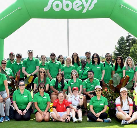 A group of Sobeys employees wearing green shirts on a golf course.