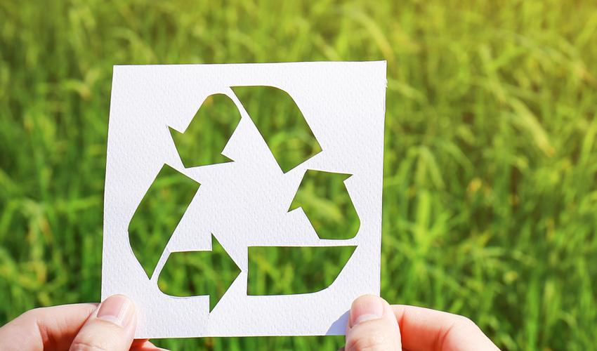Two hands holding a paper cut out of a recycling symbol.